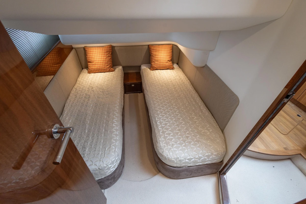 Twin cabin interior of 2013 Princess 42 yacht with cozy bedding and wooden accents.