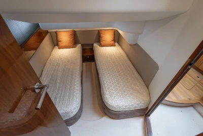 Twin cabin interior of 2013 Princess 42 yacht with cozy bedding and wooden accents.