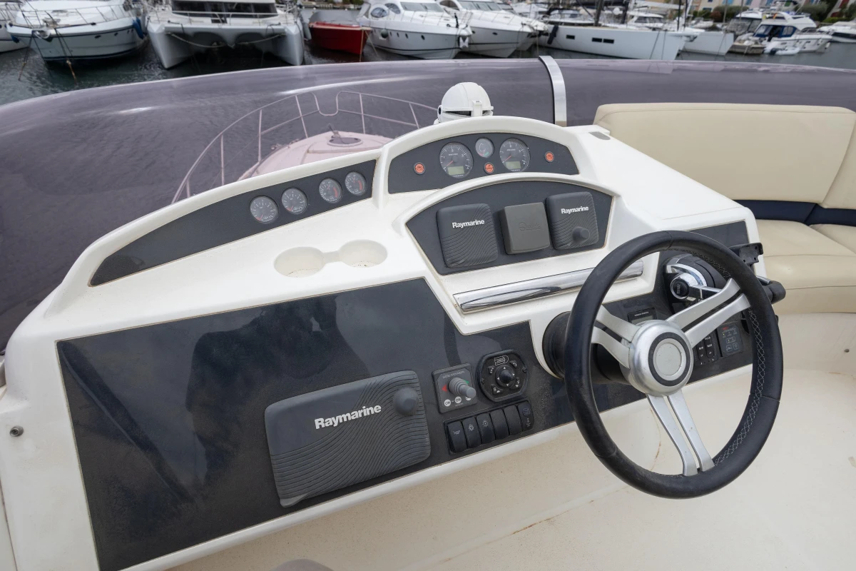 Control panel of a 2013 Princess 42 yacht with steering wheel and navigation equipment.