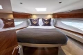 Luxurious 2023 Princess V50 yacht cabin with elegant bedding and wood accents.