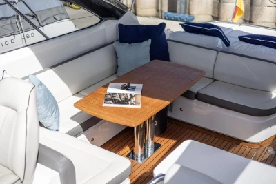 Luxurious seating area on a 2015 Princess V48 Open yacht with wooden table and cushions.