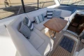 Luxurious seating area on 2006 Princess V53 yacht with striped cushions and wooden table.