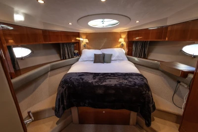 Luxurious cabin interior of 2006 Princess V53 yacht with cozy bed and elegant lighting.