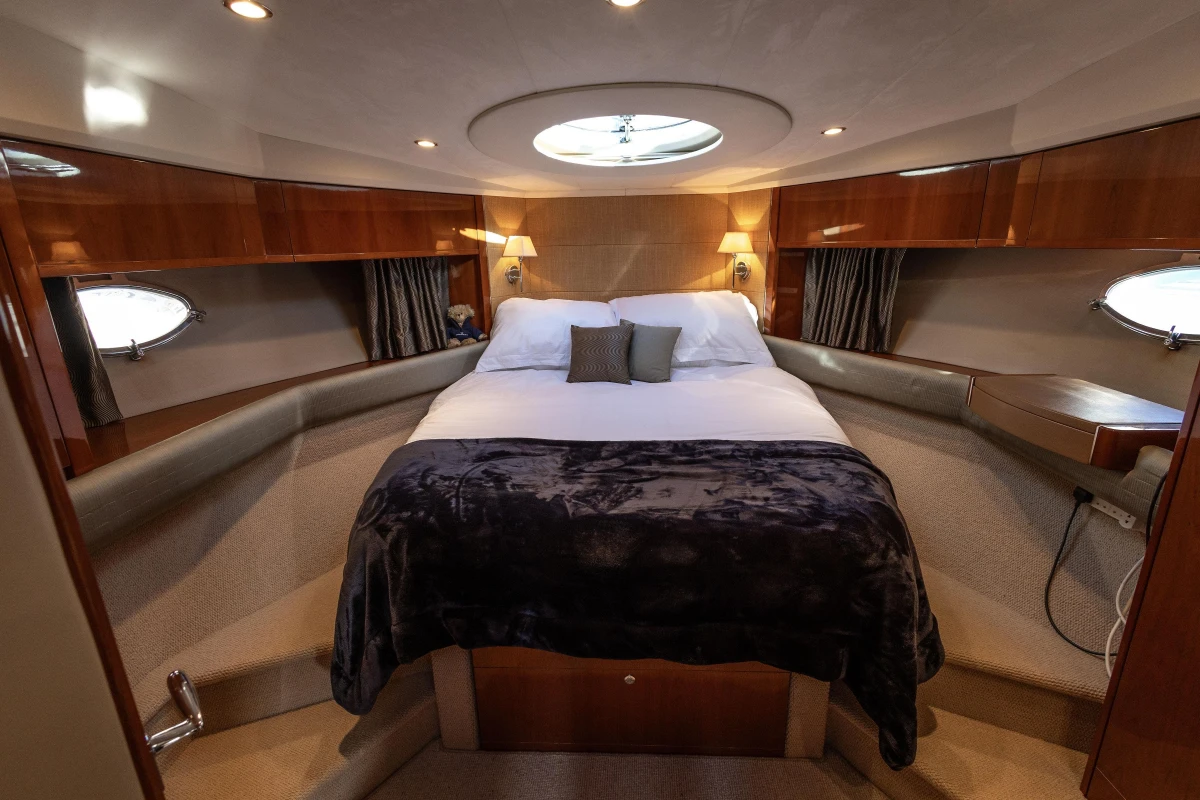 Luxurious cabin interior of 2006 Princess V53 yacht with cozy bed and elegant lighting.