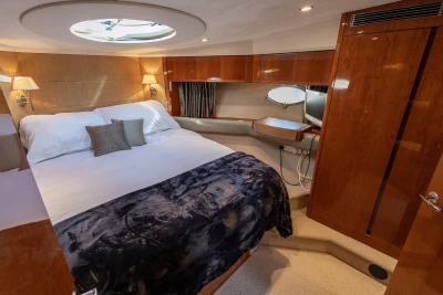 Luxurious 2006 Princess V53 yacht cabin with elegant wood finishes and cozy bedding.