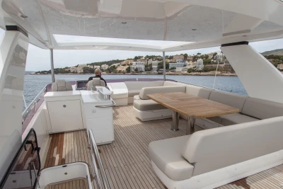 Luxurious 2015 Princess 68 yacht deck with seating and dining area, overlooking coastal scenery.