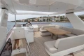 Luxurious 2015 Princess 68 yacht deck with seating and dining area, overlooking coastal scenery.