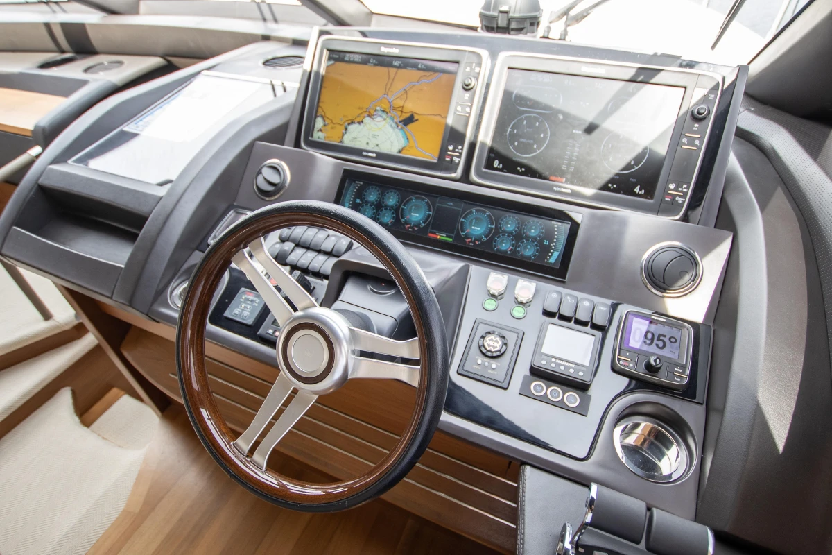 Control panel of a 2015 Princess 68 yacht with navigation screens and steering wheel.