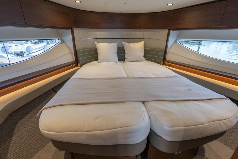 Luxurious interior of 2025 Princess V55 yacht with elegant bedding and panoramic windows.
