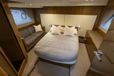 Luxurious 2014 Princess V48 yacht cabin with cozy bed and elegant wood finishes.
