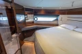 Luxurious bedroom interior of 2017 Princess 68 yacht with elegant wood finishes and large window.