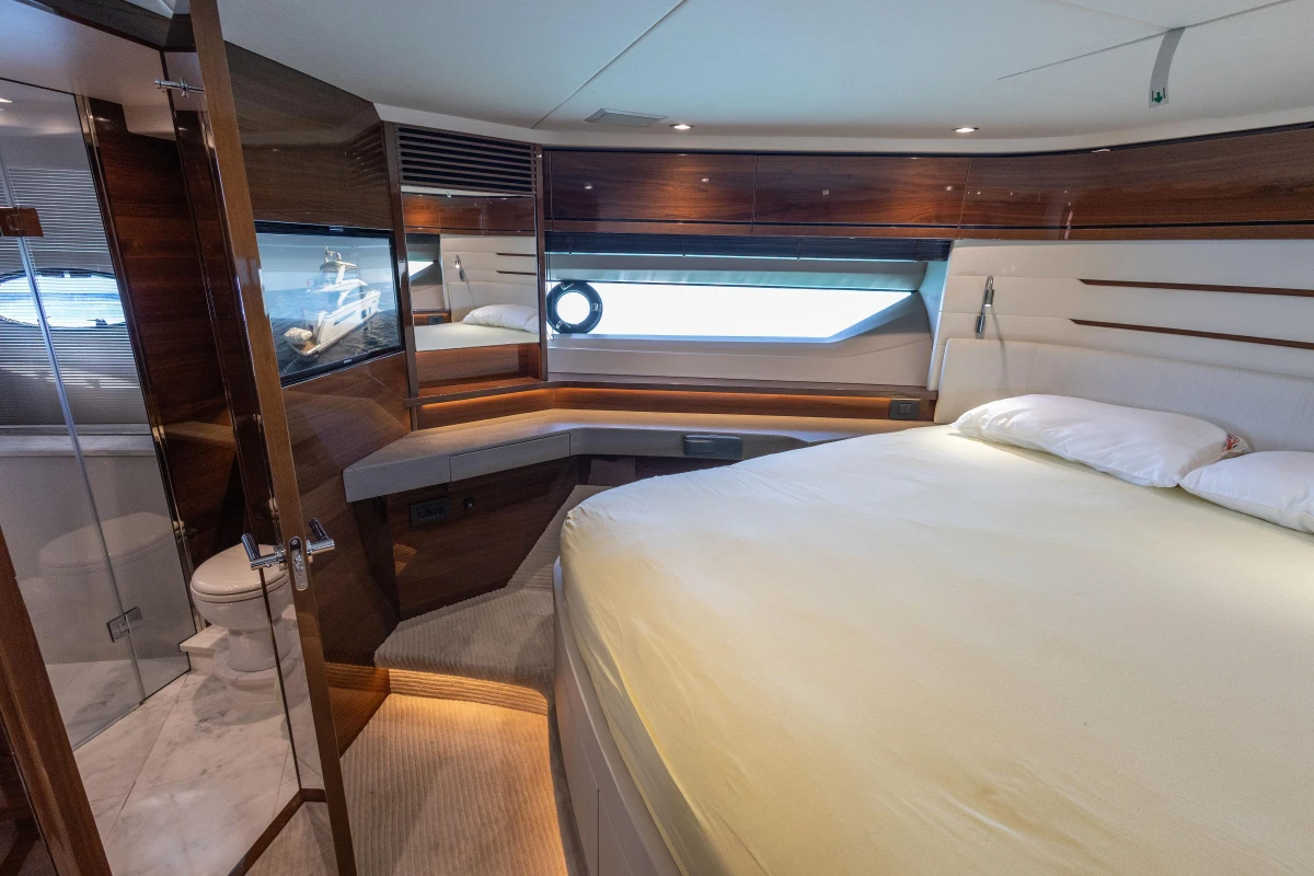Luxurious bedroom interior of 2017 Princess 68 yacht with elegant wood finishes and large window.