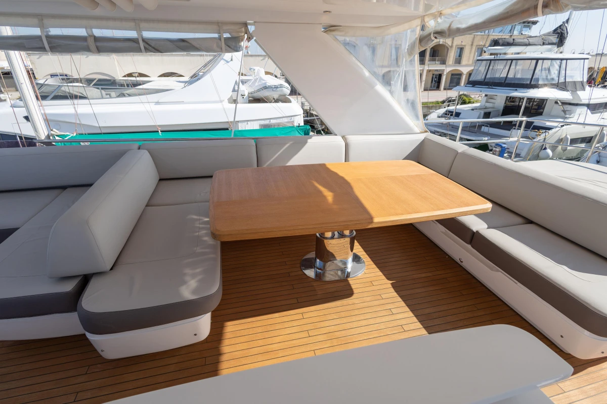 Luxurious seating area on 2017 Princess 68 yacht with wooden table and cushioned benches.
