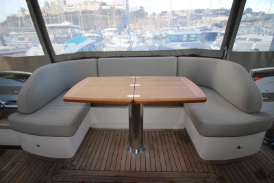 Luxurious seating area on 2017 Princess 52 yacht with wooden table and cushioned benches.