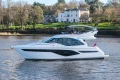 Luxury yacht Princess F50 2025 on a serene river by a mansion.