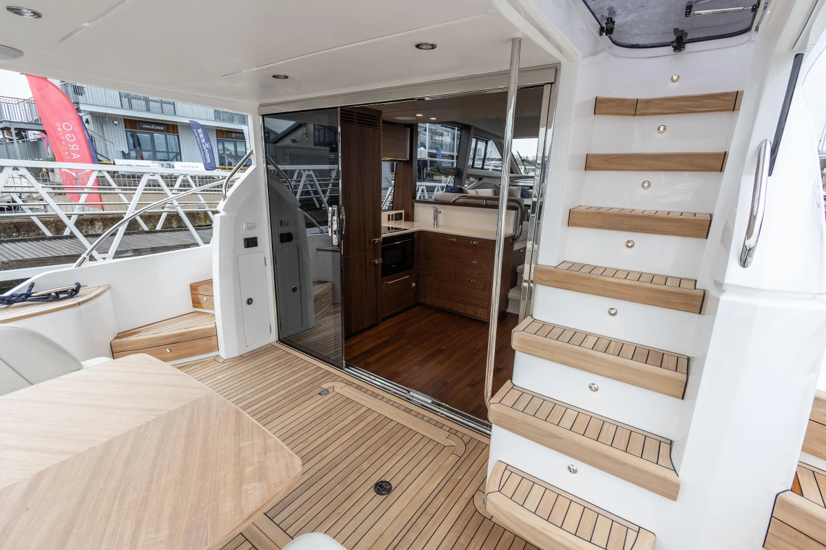 Interior of 2025 Princess F50 yacht with wooden stairs and modern kitchen.