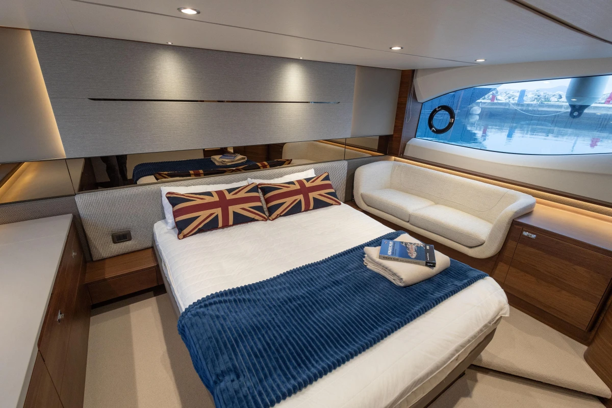 Luxurious 2022 Princess V55 yacht bedroom with modern decor and Union Jack pillows.