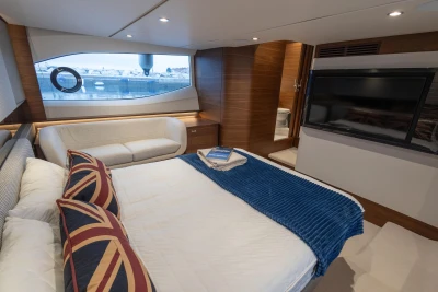Luxurious bedroom interior of 2022 Princess V55 yacht with modern decor and large window view.