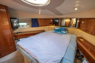 Luxurious cabin interior of 1995 Princess 60 yacht with cozy bed and wooden furnishings.