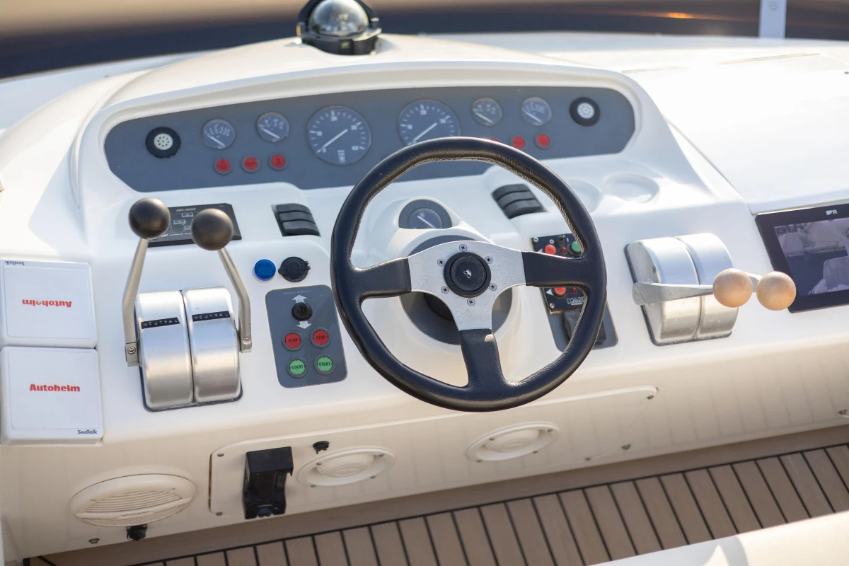 Control panel of a 1995 Princess 60 yacht with steering wheel and navigation instruments.
