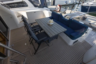 Outdoor seating area on a 1995 Princess 60 yacht with table and cushioned seats.