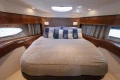 Luxurious cabin interior of 2012 Princess 50 yacht with cozy bedding and elegant wood finish.