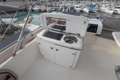 Outdoor kitchenette on 2012 Princess 50 yacht, featuring grill and sink, docked at marina.