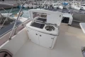 Outdoor kitchenette on 2012 Princess 50 yacht, featuring grill and sink, docked at marina.