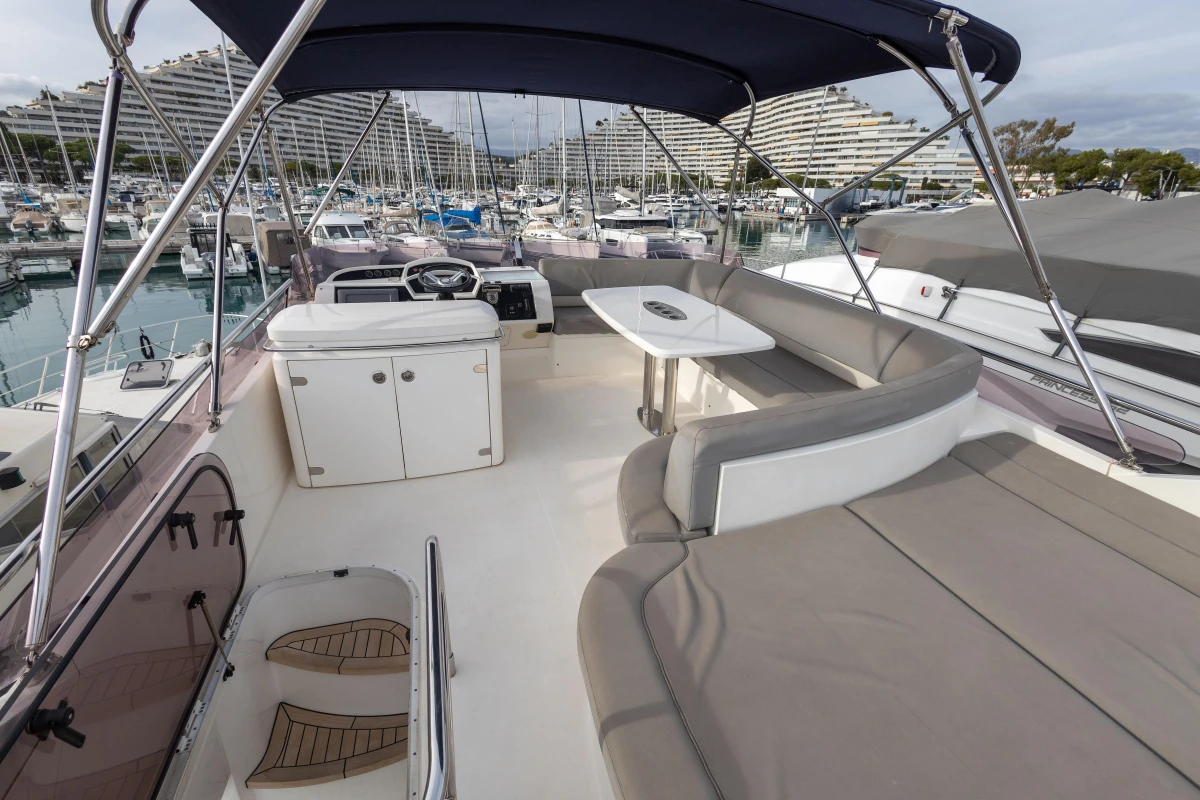 Flybridge of 2012 Princess 50 yacht with seating and table, docked in marina.