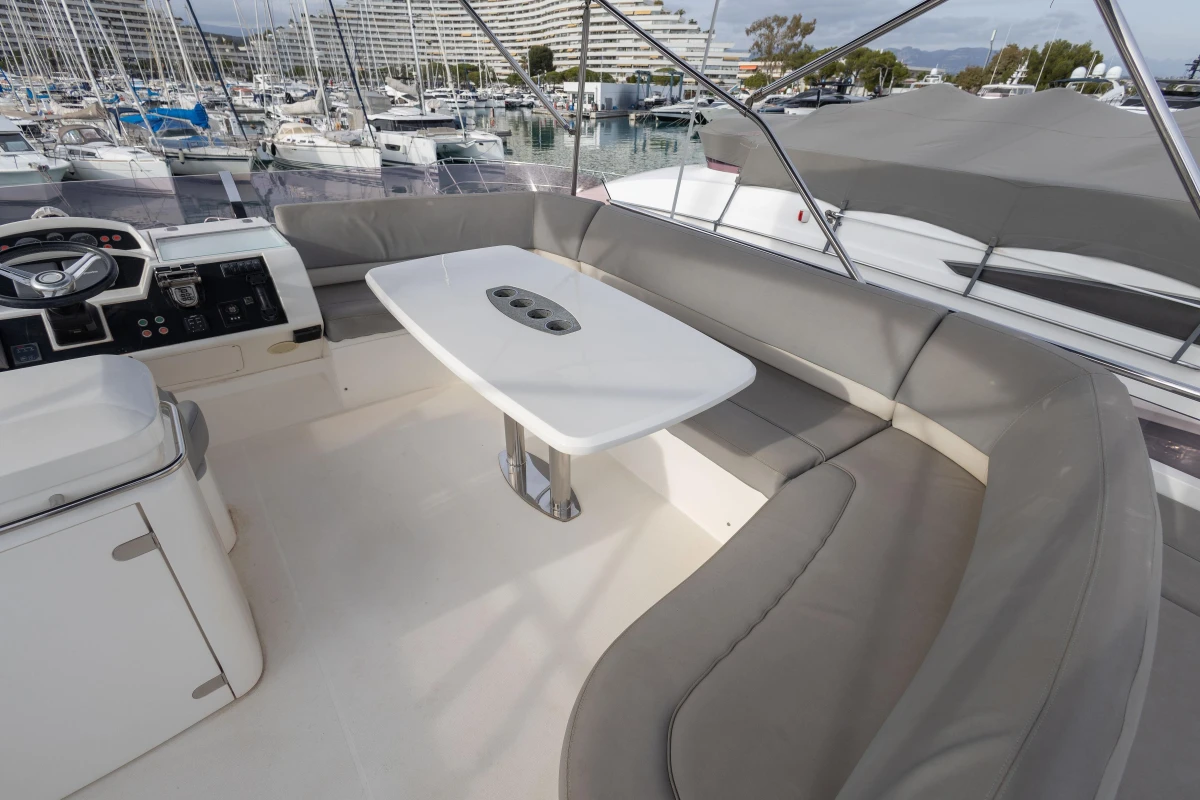 Luxurious 2012 Princess 50 yacht interior with elegant seating and table in a marina setting.
