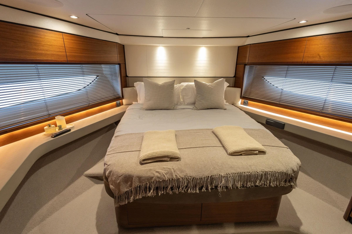 Luxurious bedroom interior of 2020 Princess F62 yacht with elegant wood accents and cozy bedding.