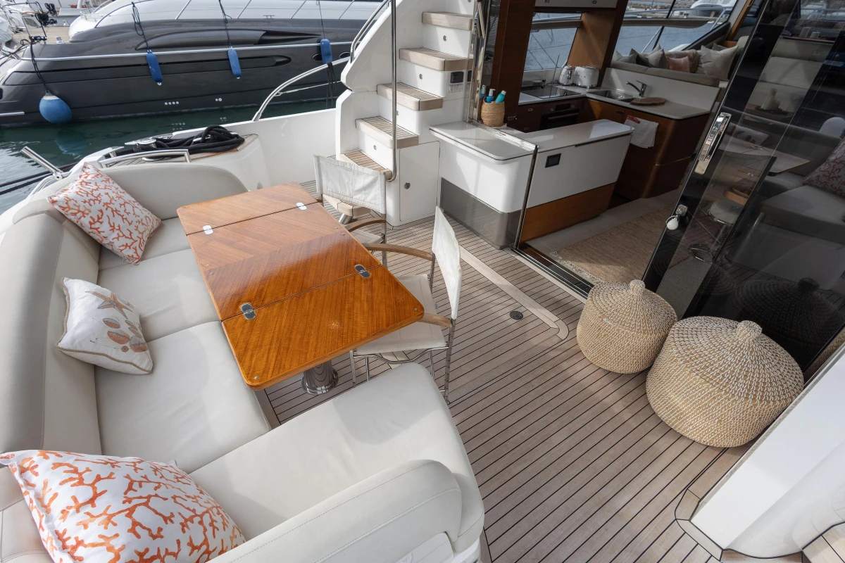 Luxurious 2020 Princess F62 yacht interior with elegant seating, wooden table, and modern kitchen area.