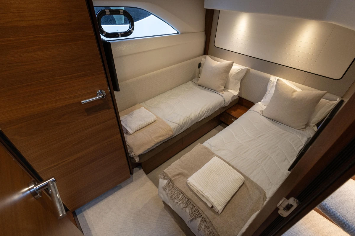 Luxurious twin cabin interior on 2020 Princess F62 yacht, featuring elegant bedding and wood finishes.