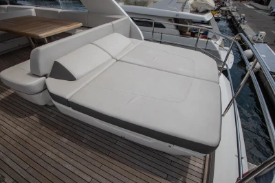 Sunbed on the deck of a luxury yacht with wooden flooring and a harbor in the background.