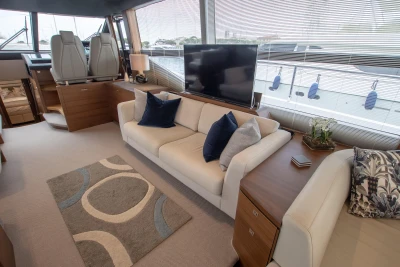 Interior of a luxury yacht with sofa, TV, and large windows.