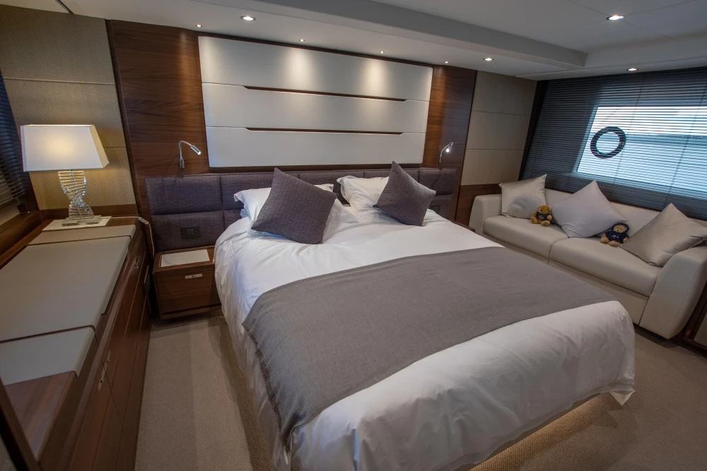 Luxurious bedroom with a double bed, sofa, and stylish lighting on a yacht.
