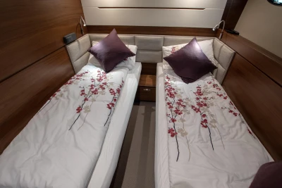 Two single beds in an elegant cabin with wood paneling and decorative pillows.