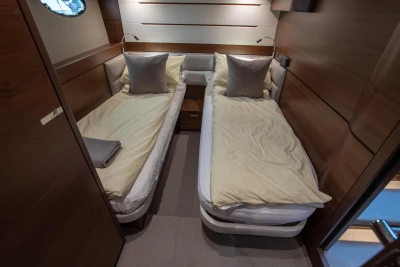 Two single beds in an elegant cabin with wooden walls and soft lighting.