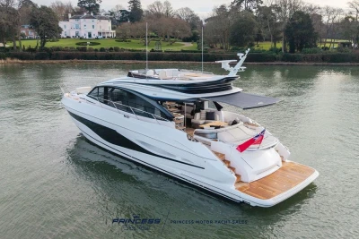 Luxurious 2026 Princess S65 yacht cruising on serene waters near elegant estate.