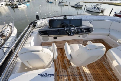 Luxurious 2026 Princess S65 yacht cockpit with modern steering and seating, docked at marina.