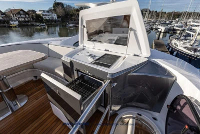 Luxury yacht Princess S65 2026 with outdoor kitchen and seating area by the marina.