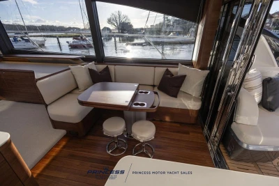 Luxurious interior of 2026 Princess S65 yacht with elegant seating and scenic marina view.