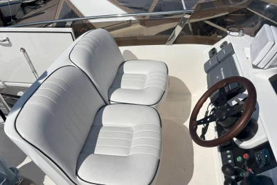Flybridge helm of 2004 Princess 45 Motor Yacht with white seating and wooden steering wheel.