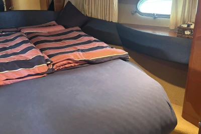 Cozy bedroom interior of 2004 Princess 45 Flybridge Motor Yacht with striped bedding.