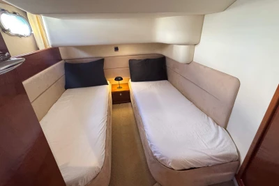 Twin cabin interior of 2006 Princess 42 yacht with beige upholstery and bedside lamp.