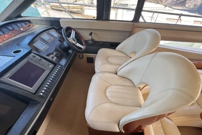Interior helm of 2006 Princess 42 yacht with dual white captain chairs and navigation controls.