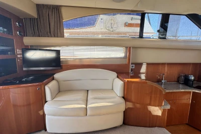 Luxurious interior of a 2006 Princess 42 yacht with sofa, TV, and kitchenette.