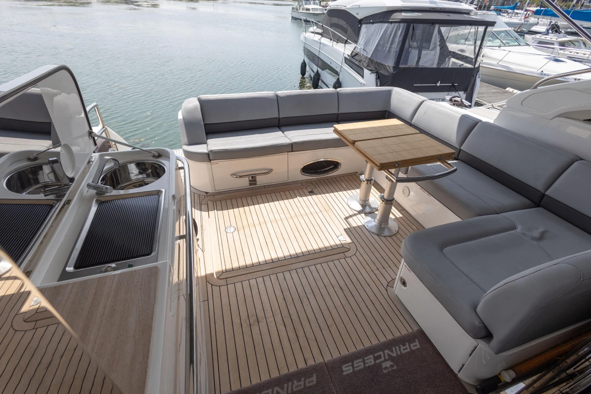 Luxurious 2014 Princess V52 yacht deck with seating and table, docked by the water.