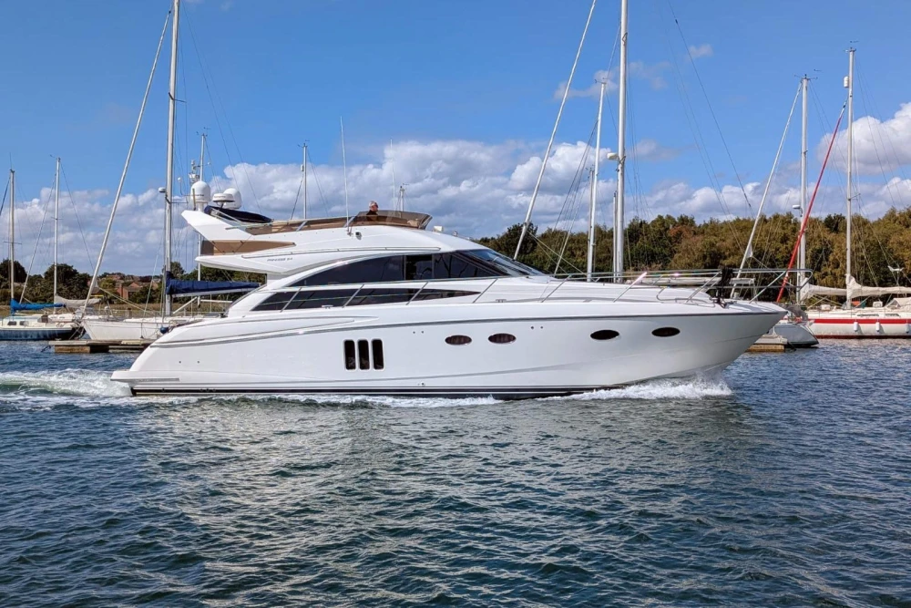 2009 Princess 54 yacht cruising in a marina under a clear blue sky.