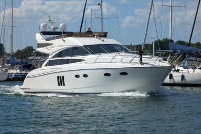 Luxurious 2009 Princess 54 yacht cruising in a marina under a clear blue sky.